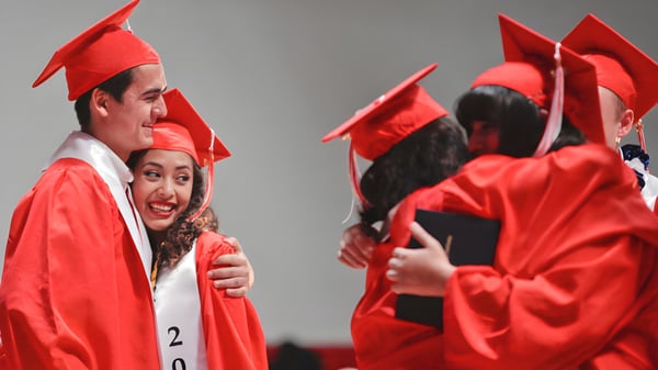 Schüler der Freedom Preparatory Academy feiern gemeinsam in roten Abschlussroben und -kappen ihren Erfolg.