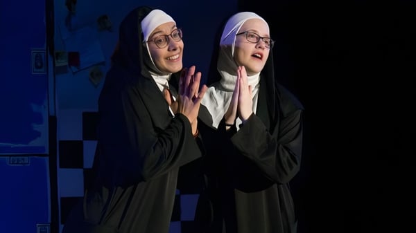 Zwei Schülerinnen der Freedom Preparatory Academy tragen traditionelle religiöse Kleidung vor blauem Hintergrund.