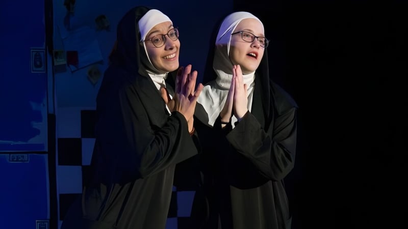 Zwei Schülerinnen der Freedom Preparatory Academy tragen traditionelle religiöse Kleidung vor blauem Hintergrund.