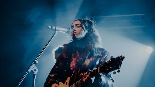 Eine Schülerin des Fremantle College spielt Gitarre und singt auf der Bühne unter blauem Licht.