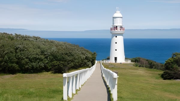 Ein weißer Leuchtturm steht auf einem grasbewachsenen Hügel mit Blick auf den Ozean in der Nähe des Fremantle College.