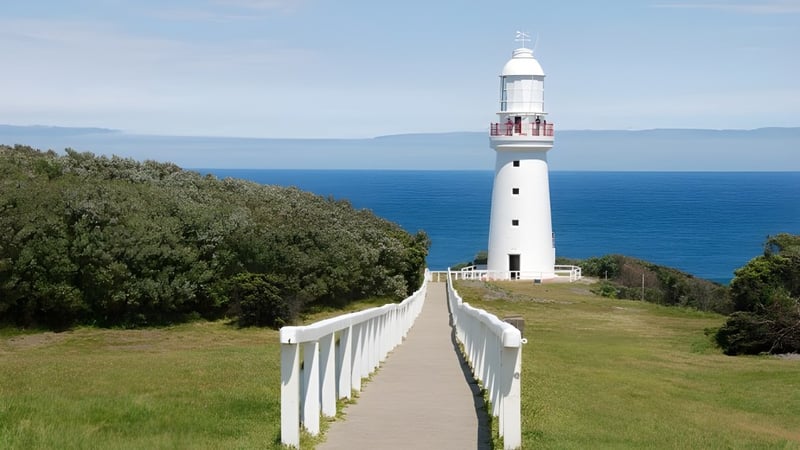 Ein weißer Leuchtturm steht auf einem grasbewachsenen Hügel mit Blick auf den Ozean in der Nähe des Fremantle College.