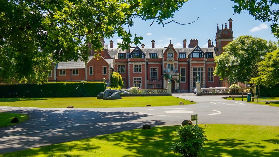 Das historische Gebäude der Frensham Heights School ist von einem gepflegten Garten mit Weg und Hecken umgeben.