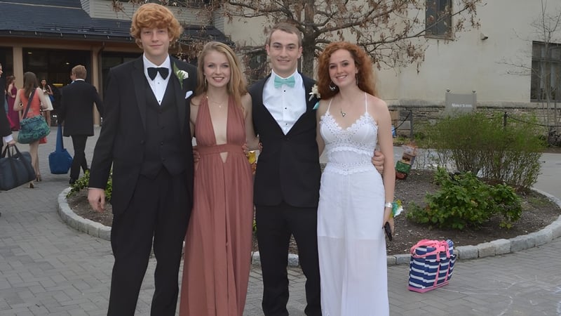 Vier Schülerinnen und Schüler der Friends School of Baltimore stehen gemeinsam in formeller Kleidung im Außenbereich vor einem gepflasterten Weg.