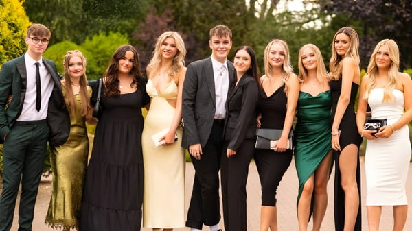 Eine Gruppe von gut gekleideten Schülerinnen und Schülern posiert im Freien auf dem Campus des Frome College vor Bäumen und Grün.