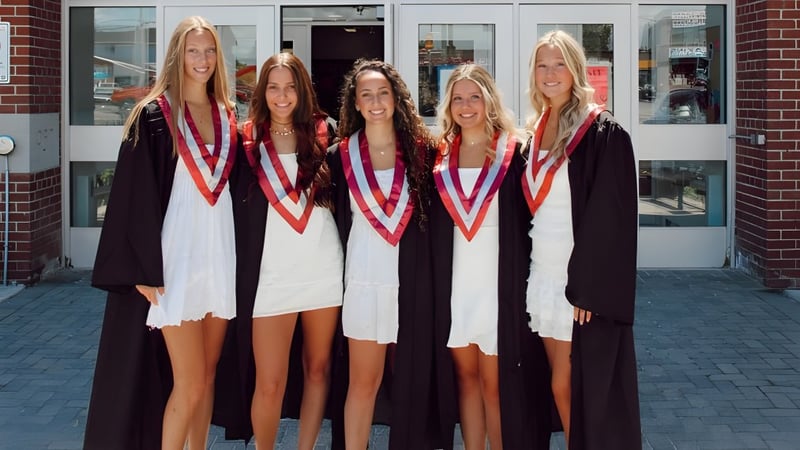 Fünf Absolventinnen stehen vor einem Backsteingebäude auf dem Campus der Frontenac Secondary School und feiern ihren Abschluss.