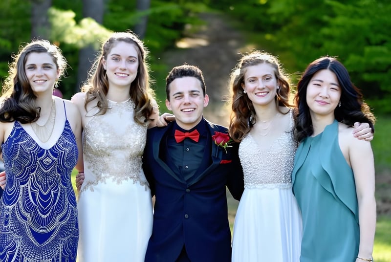 Eine Gruppe von fünf Schülern posiert gemeinsam in einem grünen Außenbereich auf dem Campus der Fryeburg Academy.