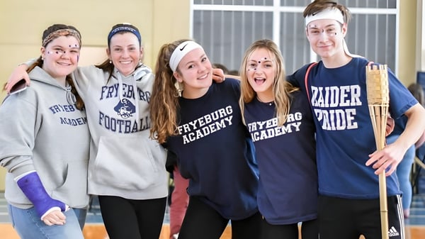 Eine Gruppe von fünf Schülerinnen und Schülern steht zusammen und lächelt auf dem Campus der Fryeburg Academy.