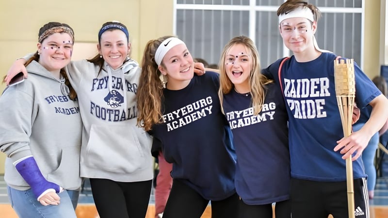 Eine Gruppe von fünf Schülerinnen und Schülern steht zusammen und lächelt auf dem Campus der Fryeburg Academy.