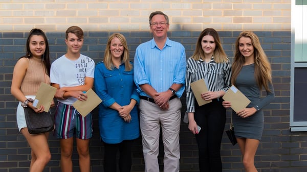 Eine Gruppe von sechs Personen steht vor einer Backsteinwand auf dem Gelände der Fulston Manor School.