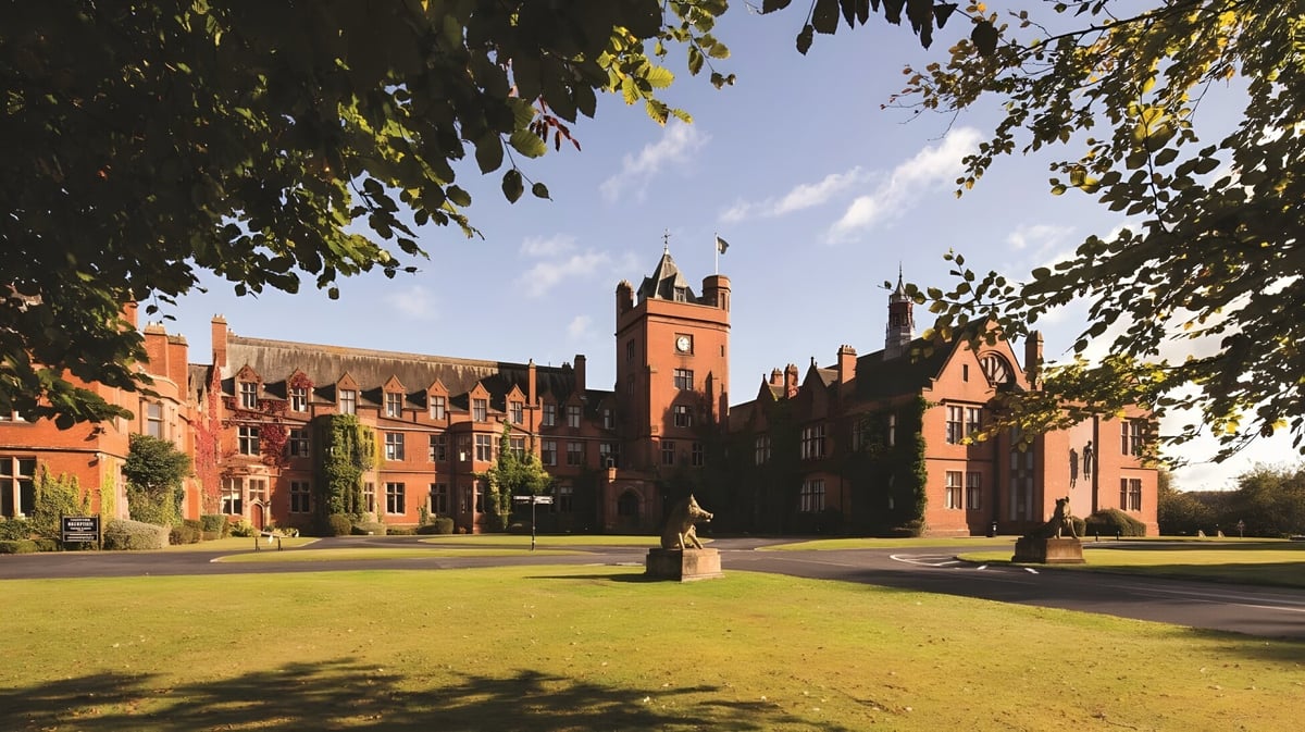 Das historische Hauptgebäude der Fyling Hall School steht in einem grünen Innenhof unter blauem Himmel.