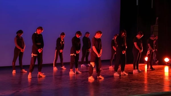 Schüler der G.W. Graham Secondary School stehen in einem Theaterraum mit roter und blauer Beleuchtung.