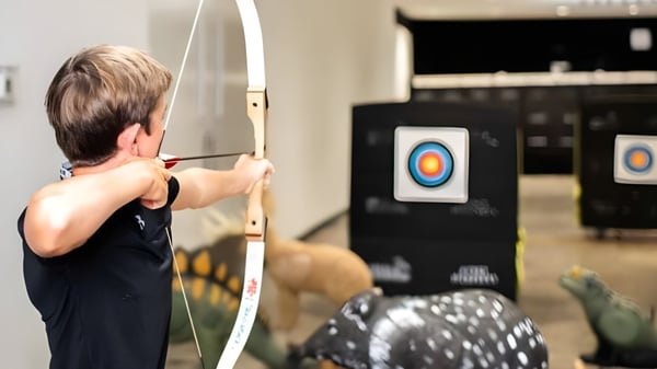 Ein Schüler der Gallen Community School zielt mit einem Bogen auf eine Zielscheibe im Hintergrund.