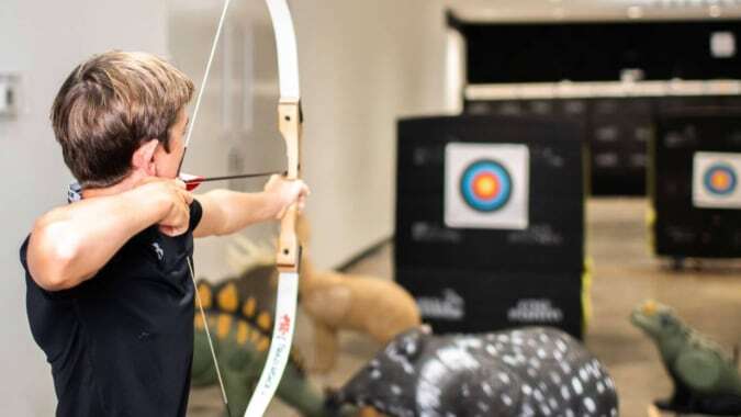 Eine Schülerin der Gallen Community School zielt mit einem Bogen auf Zielscheiben im Hintergrund.