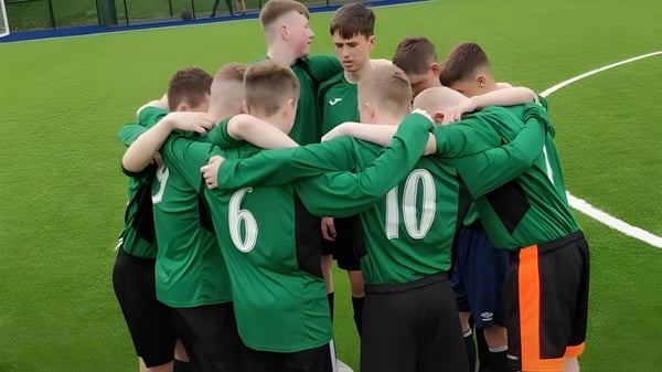 Eine Gruppe von jungen Fußballspielern in grünen Trikots auf dem Spielfeld der Gallen Community School.
