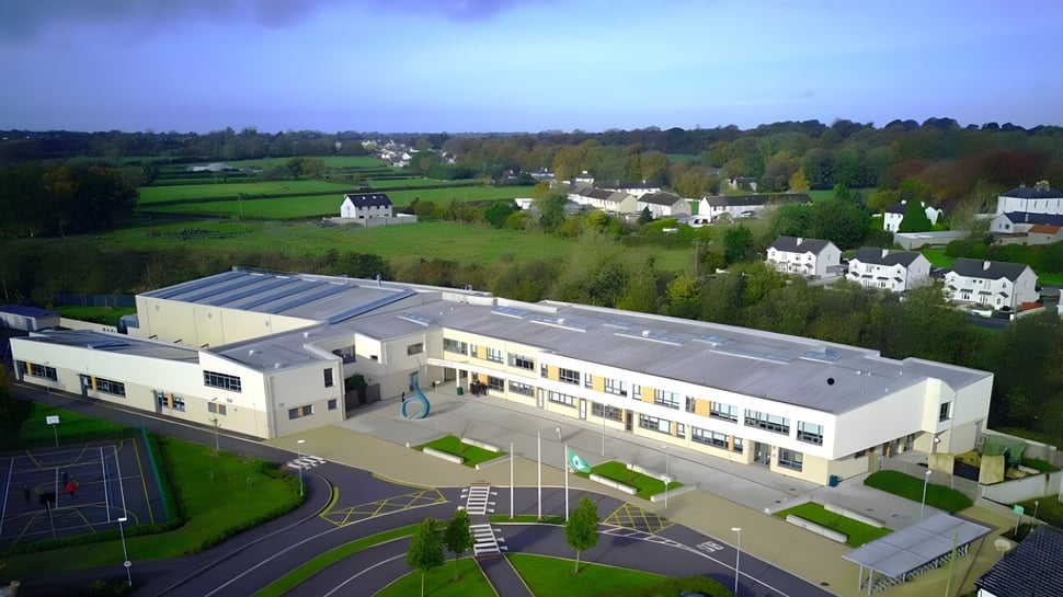 Das moderne mehrstöckige Gebäude der Gallen Community School ist von einer ländlichen Landschaft mit Hügeln und Wald umgeben.