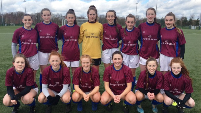 Ein Team junger Fußballspielerinnen des Galway Community College steht gemeinsam auf dem Spielfeld.