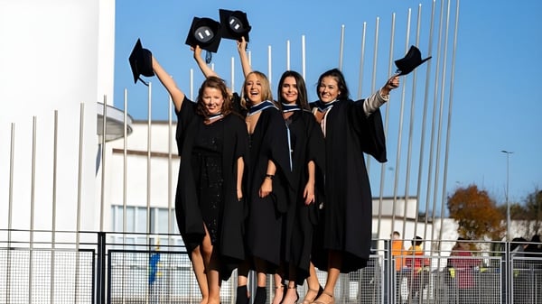 Eine Gruppe von vier Schülerinnen feiert ihre Graduierung auf dem Campus des Galway Community College.