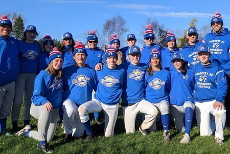 Eine Gruppe Schüler der Gander Collegiate steht in blauen Uniformen auf einer Wiese unter klarem Himmel.