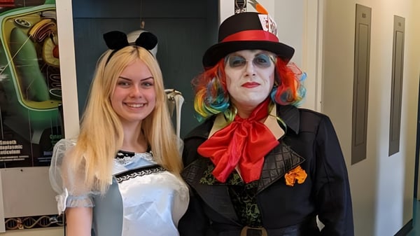 Zwei Personen in bunten Theaterkostümen stehen in einem Raum auf dem Campus der Gander Collegiate.