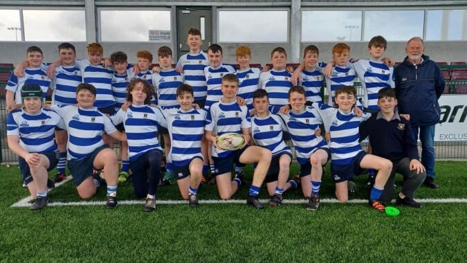 Schülerinnen des Garbally College stehen auf einem Rasenfeld vor einer Sportanlage.