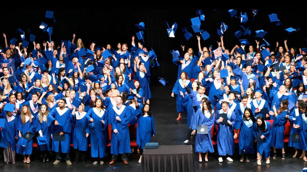 Eine Gruppe von Schülerinnen und Schülern der Garibaldi Secondary School trägt blaue Abschlussroben bei einer Abschlussfeier auf einer Bühne.