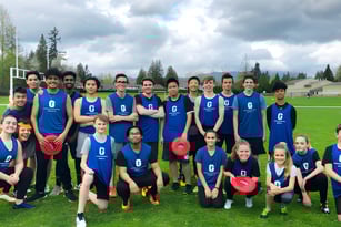 Eine Gruppe Schüler in blauer Uniform steht auf einem Grasfeld vor Bäumen auf dem Gelände der Garibaldi Secondary School.