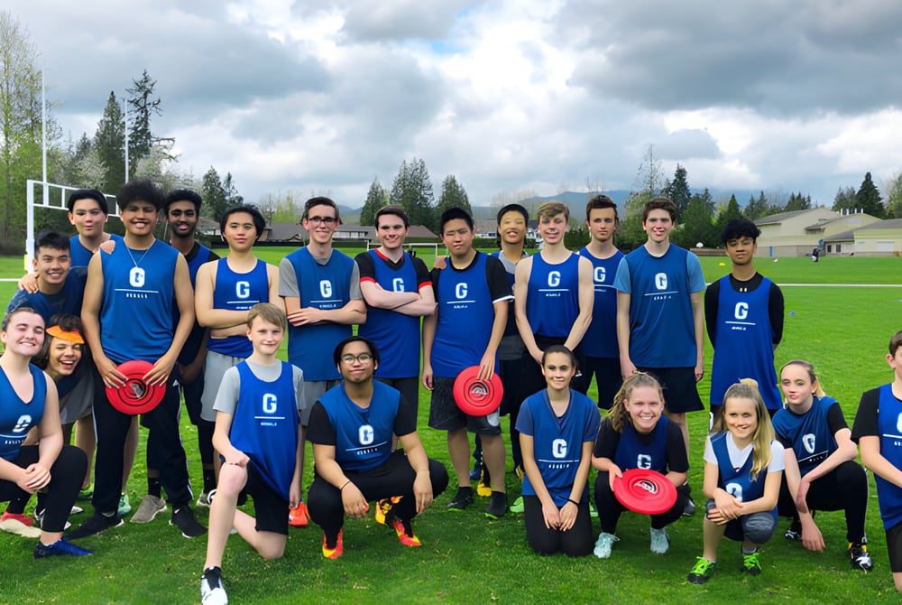 Eine Gruppe Schüler in blauer Uniform steht auf einem Grasfeld vor Bäumen auf dem Gelände der Garibaldi Secondary School.