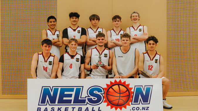 Eine Gruppe junger Basketballspielerinnen und -spieler des Garin College posiert gemeinsam vor einem Nelson Basketball Banner und hält einen Pokal.