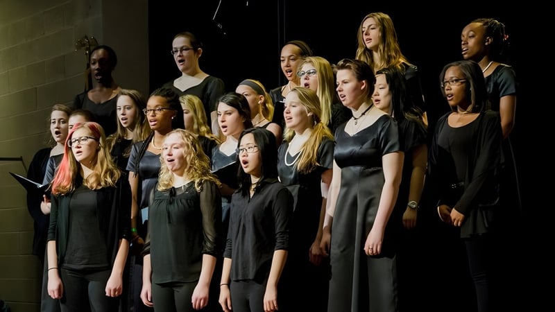 Schüler der Garrison Forest School führen gemeinsam auf einer Bühne auf.