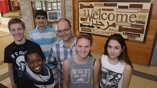 Eine Gruppe Schülerinnen und Schüler steht vor einem Willkommensschild auf dem Campus der Garth Webb Secondary School.
