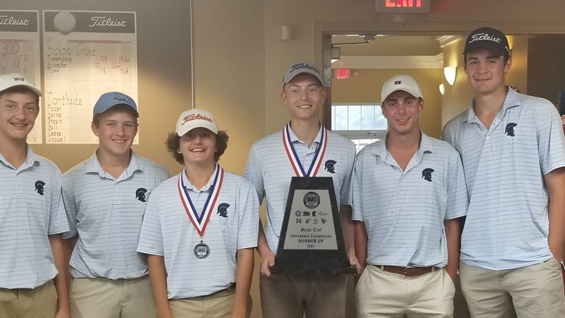 Eine Gruppe Schüler der Gaston Day School steht mit einer Trophäe in der Schulkorridor vor Whiteboards.
