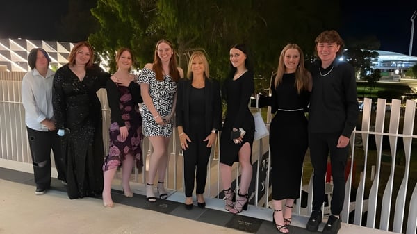 Eine Gruppe gut gekleideter Schülerinnen und Schüler steht abends mit Bäumen im Hintergrund auf dem Gelände des Gawler and District College.