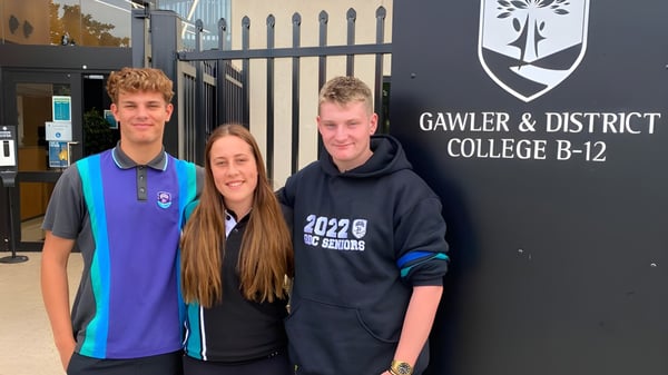 Drei Schüler stehen vor dem Schild des Gawler and District College.