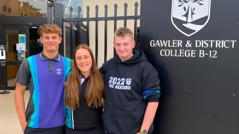 Drei Schüler stehen vor dem Schild des Gawler and District College.