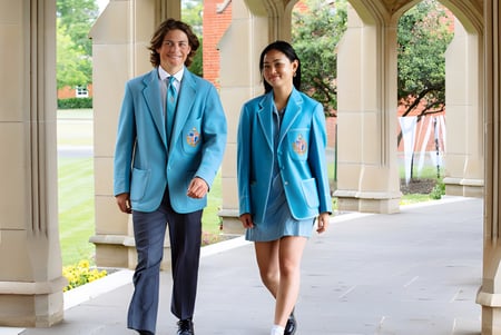 Zwei Personen stehen im Flur mit bogenförmigen Fenstern auf dem Campus der Geelong Grammar School.