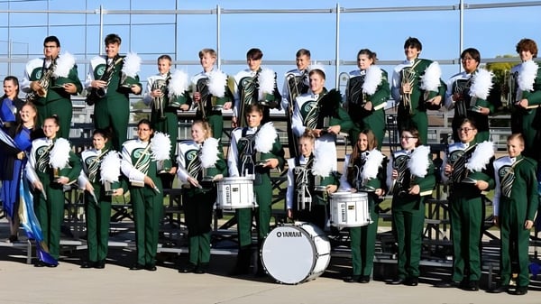 Schüler der Gehlen Catholic School posieren mit ihren Instrumenten vor einem Glasgebäude.