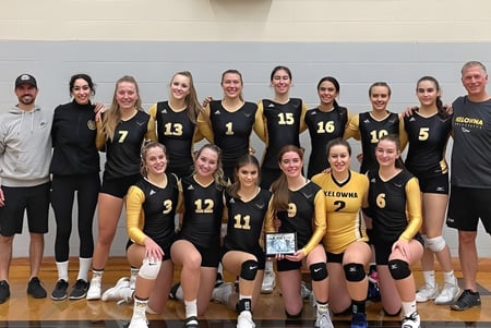 Eine Gruppe weiblicher Volleyballspielerinnen der George Elliot Secondary School steht auf dem Basketballfeld und posiert gemeinsam.