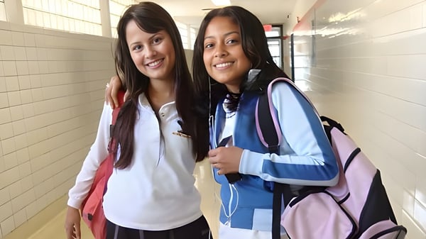 Zwei Schülerinnen stehen lächelnd im Flur des George Harvey Collegiate Institute und unterhalten sich.