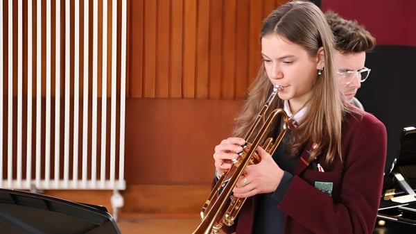 Eine Schülerin des George Watson’s College spielt Posaune in einem Raum mit holzvertäfelten Wänden.