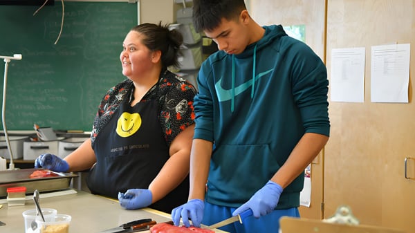 Zwei Schülerinnen und Schüler der Georges P. Vanier Secondary School arbeiten gemeinsam in einem Labor mit Schutzhandschuhen.