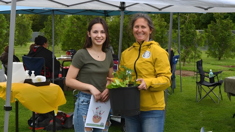 Zwei Personen stehen vor einer grünen Wiese mit Campingausrüstung auf dem Gelände der Georges P. Vanier Secondary School.