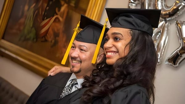 Ein älterer Mann und eine jüngere Frau in Abschlusskleidung posieren gemeinsam bei der Abschlussfeier der Georgetown District High School.