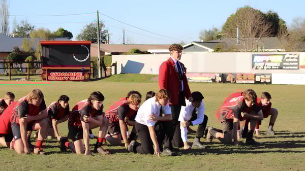 Eine Gruppe von Schülerinnen und Schülern der Geraldine High School versammelt sich auf dem Sportfeld vor einem roten Anhänger und Gebäuden.