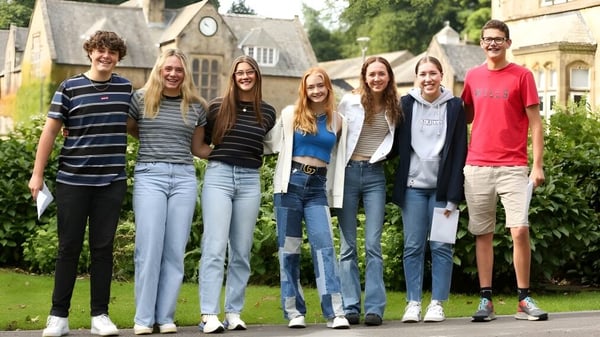 Eine Gruppe von Schülerinnen und Schülern steht vor einem Gebäude mit Garten auf dem Campus der Giggleswick School.