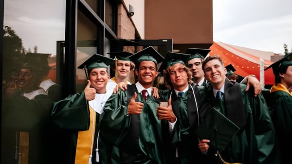 Eine Gruppe von Absolventen in grünen Talaren steht vor einem Gebäude und feiert ihren Abschluss an den Gilbert Christian Schools.