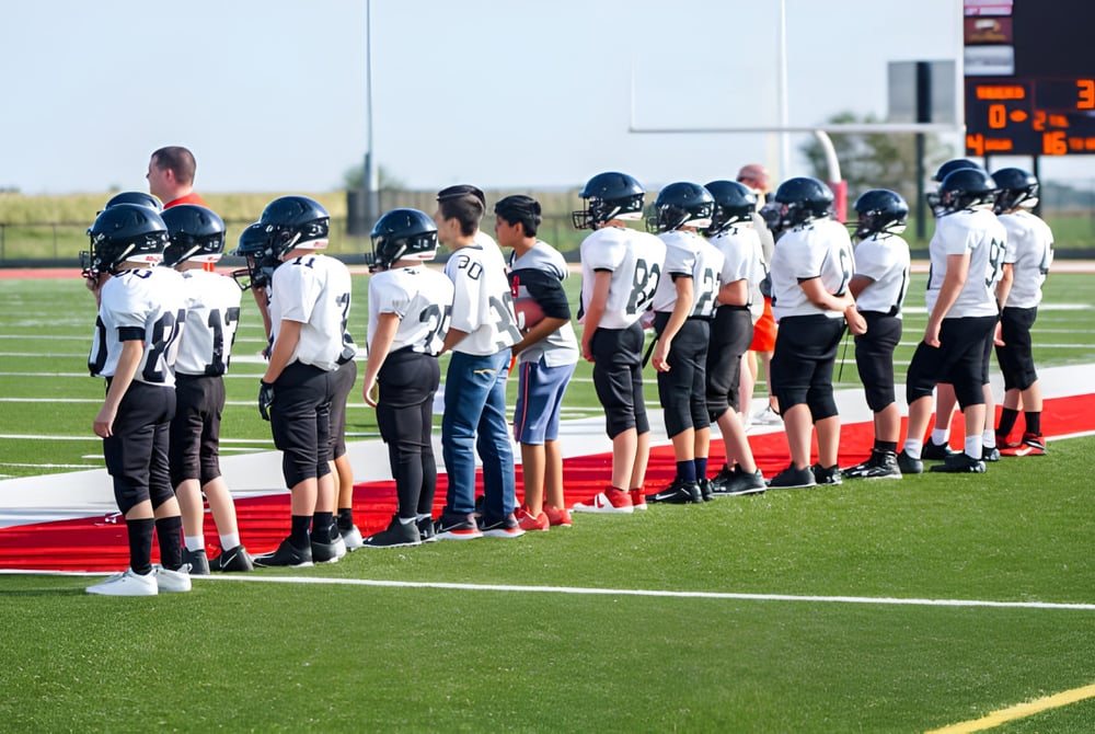 Eine Gruppe von Fußballspielern in Uniform steht auf dem Spielfeld bei Gilbert Public Schools vor einer Anzeigetafel.