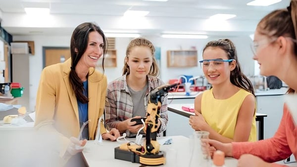 Eine Gruppe junger Schülerinnen unterhält sich und untersucht ein Objekt auf einem Tisch bei Gilbert Public Schools.