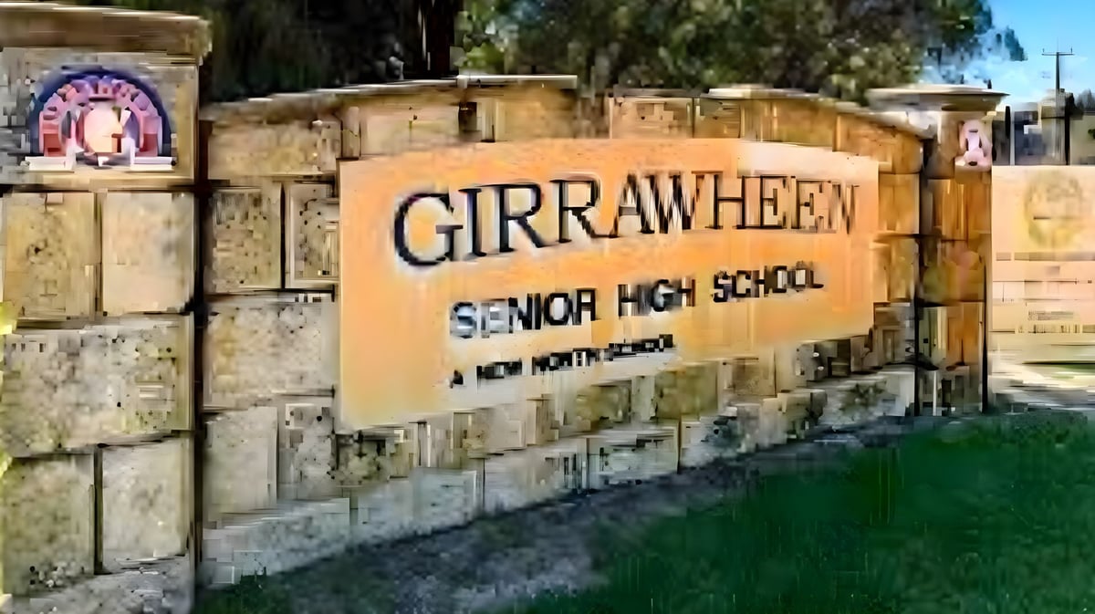 Die Steintafel mit dem Schriftzug Girrawheen Senior High School steht vor Bäumen und Gebäuden auf dem Schulgelände.