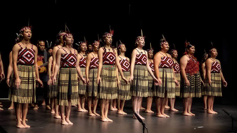 Eine Gruppe von Schülerinnen der Gisborne Girls' High School steht auf der Bühne in traditionellen tribal-inspirierten Kostümen mit aufwendigen Mustern.